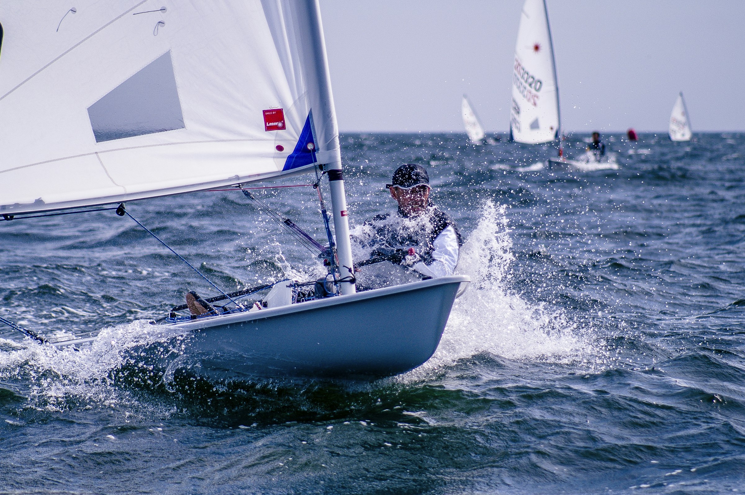 Velejador em barco de classe olímpica cortando ondas em regata
